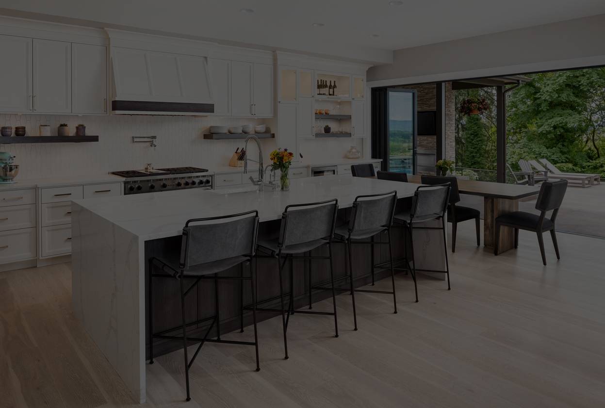 beautiful kitchen in new luxury home with island, pendant lights, oven, range, and hardwood floors.